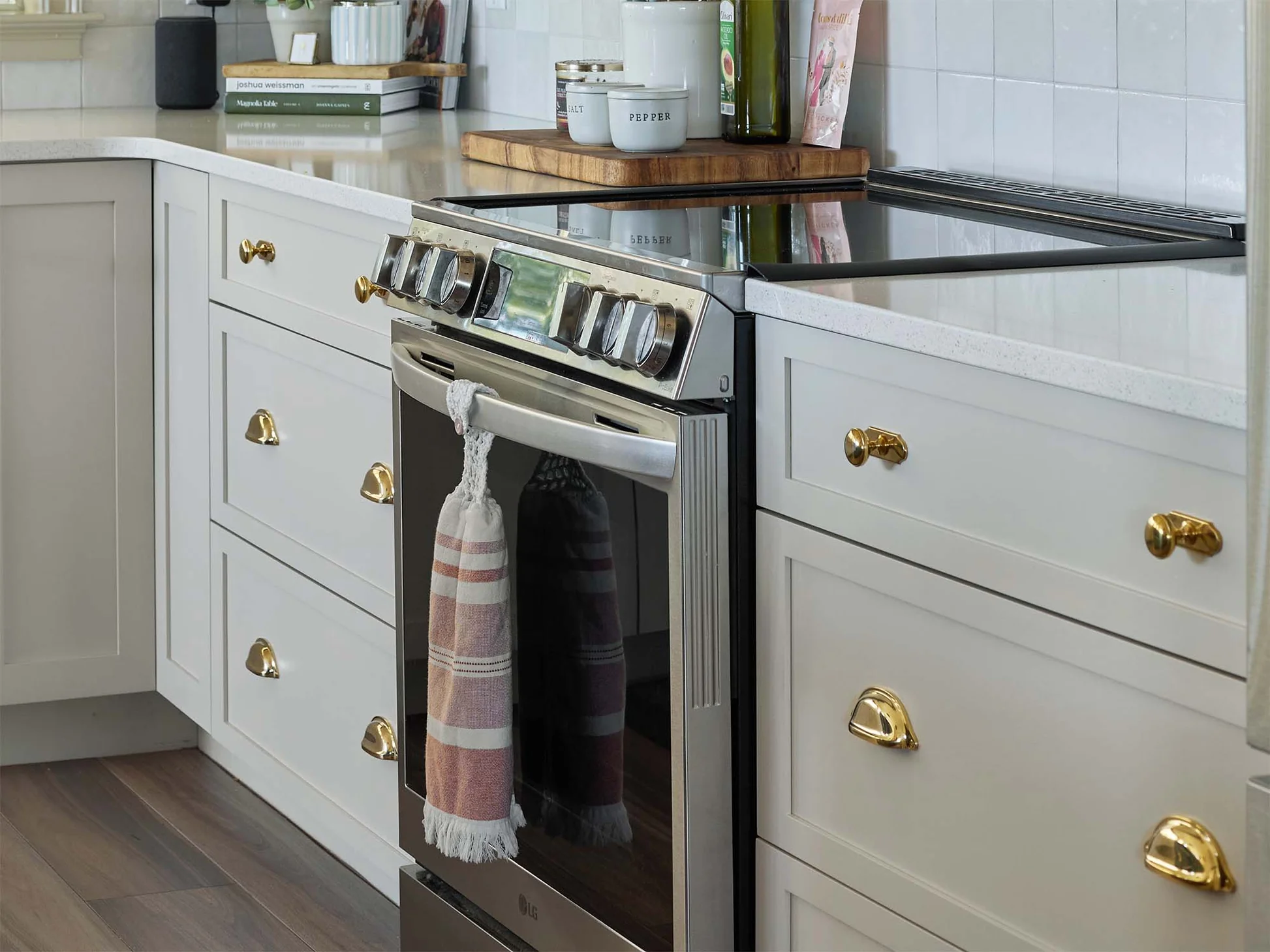 A bright kitchen with stainless steel appliances, brushed brass cabinet pulls, and a matte black bar stool base