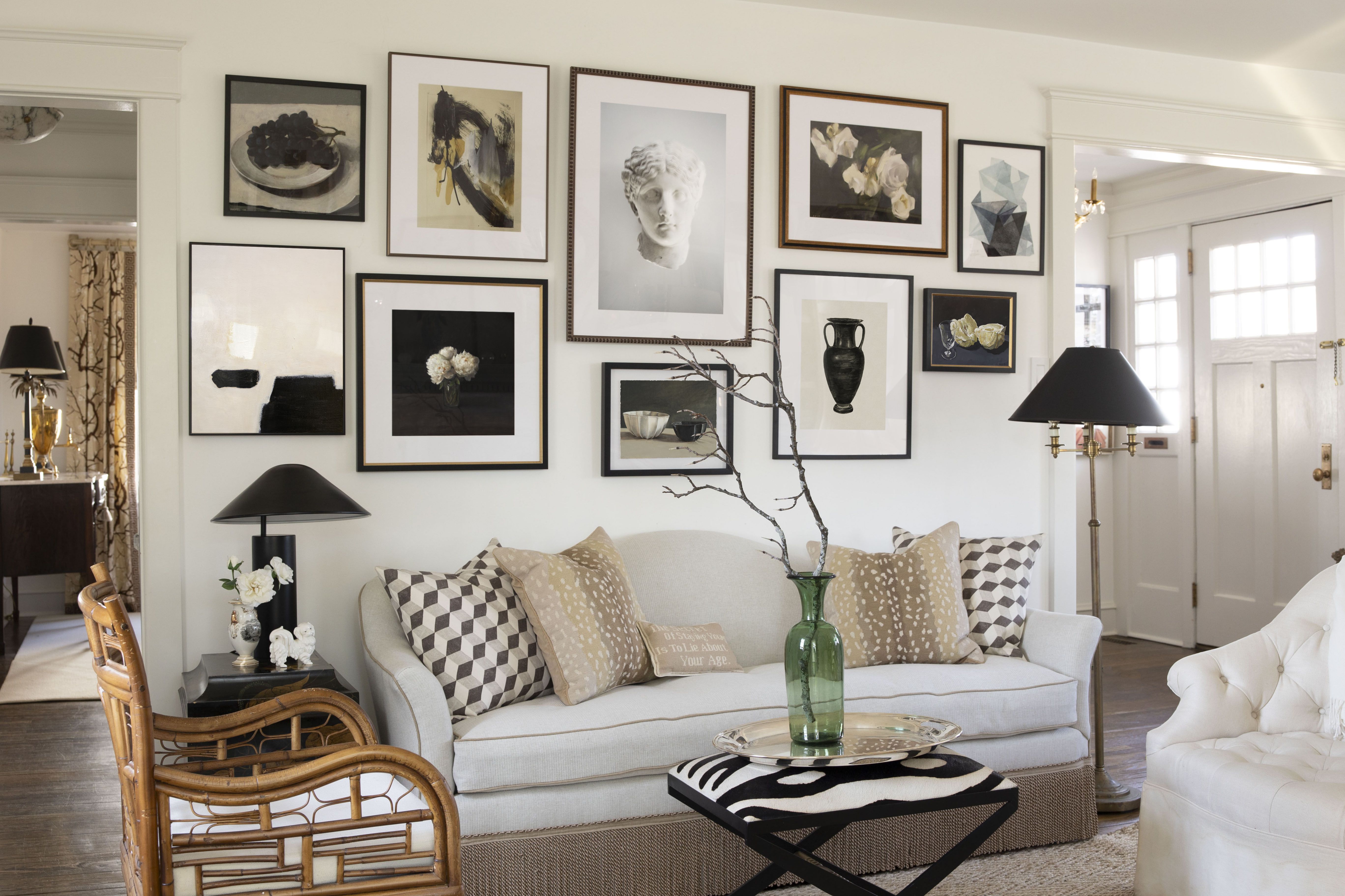 A bright rental living room with a curated gallery wall above a sofa, featuring mixed frame sizes in neutral tones and soft natural light