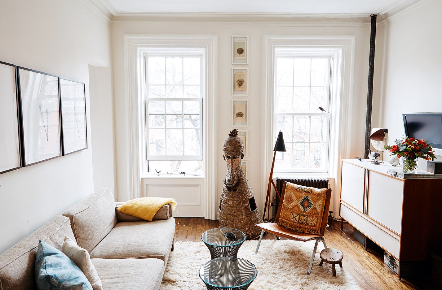 A bright, small living room with a compact sofa, a round coffee table, and a clear walking path near a window, photographed in natural daylight