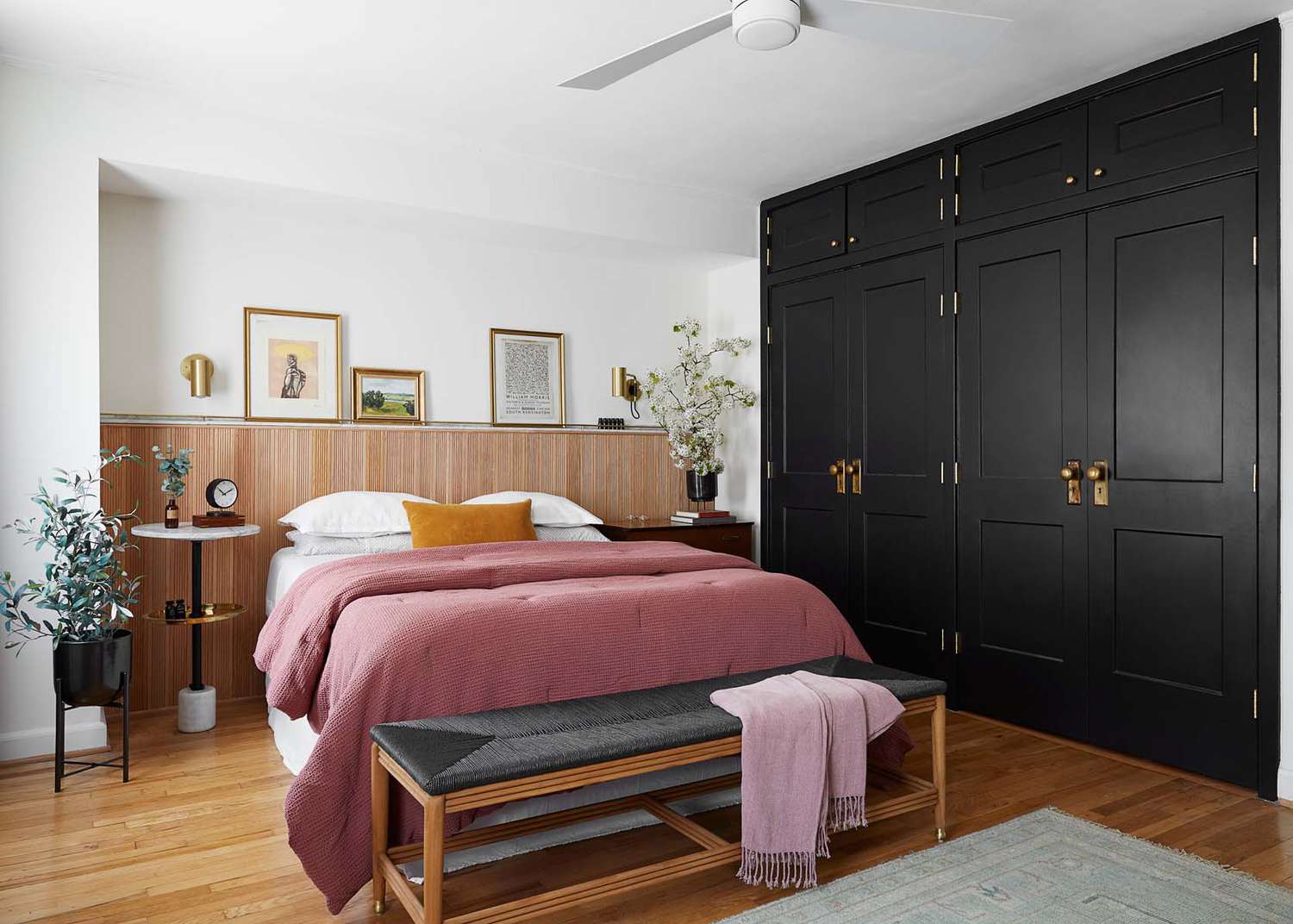 A calm bedroom with a medium wood bed frame, lighter wood nightstands on either side, and a large neutral rug grounding the mix