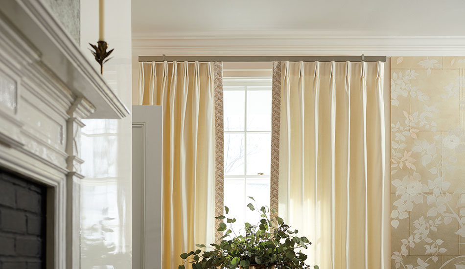 A close view of a curtain rod mounted several inches above a window frame with fabric panels falling straight to the floor