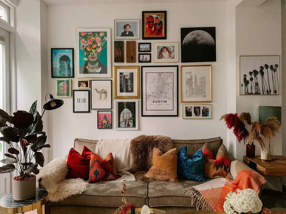 A cozy living room with a sofa and a well-spaced gallery wall of mixed frames arranged in a cohesive rectangle above the couch