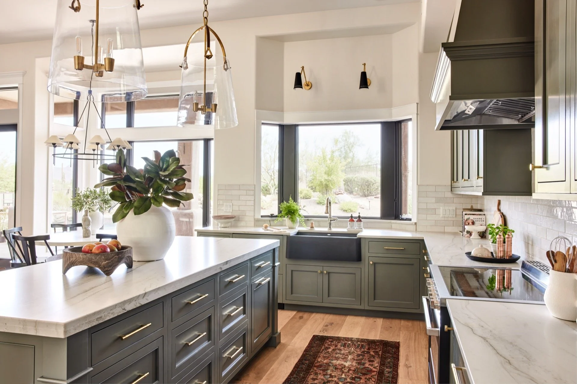 A dining nook with a brass pendant light and two matte black wall sconces, with neutral walls and a wood table