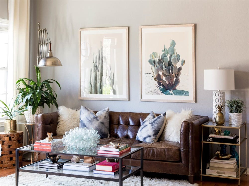 A living room sofa with two matching framed prints hung side by side above it with a small even gap