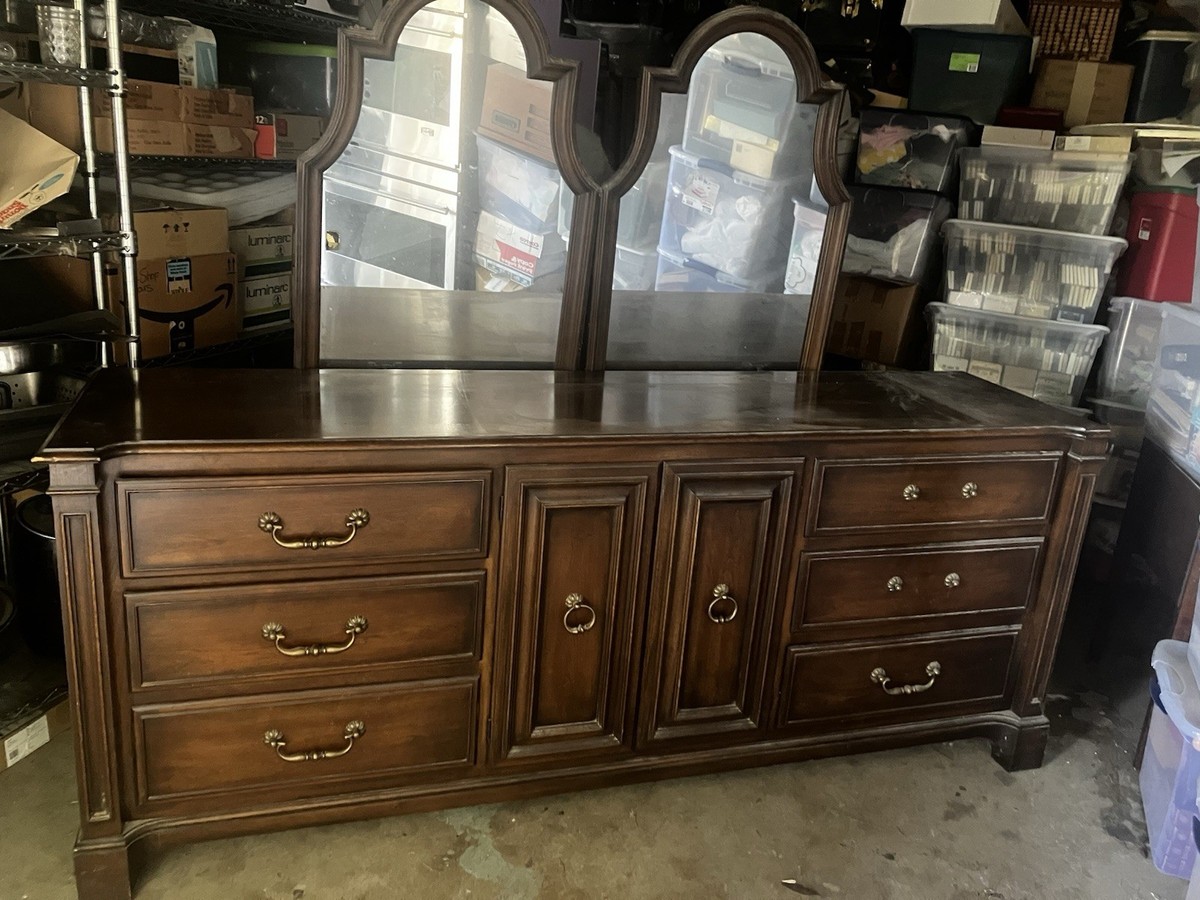 A long double dresser with two matching round mirrors hung above it, each centered over a table lamp for a balanced, symmetrical bedroom look