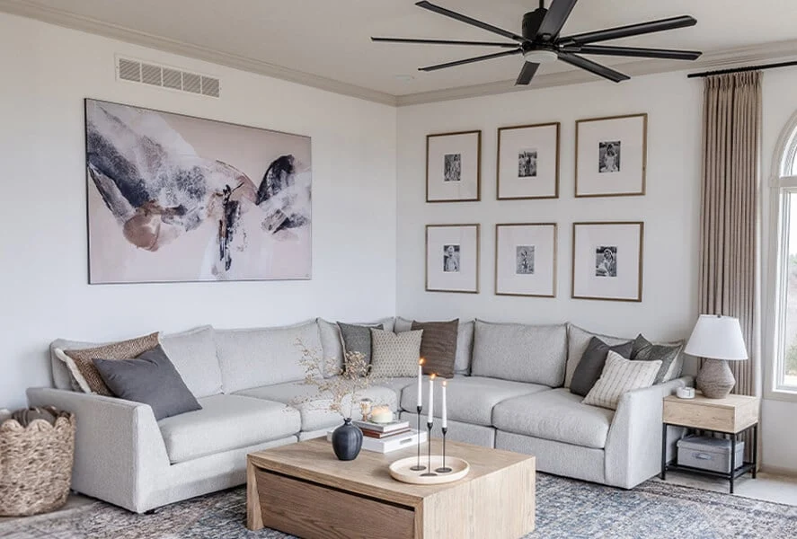 A modern sofa with one large statement painting centered above it, framed in wood, in a bright living room