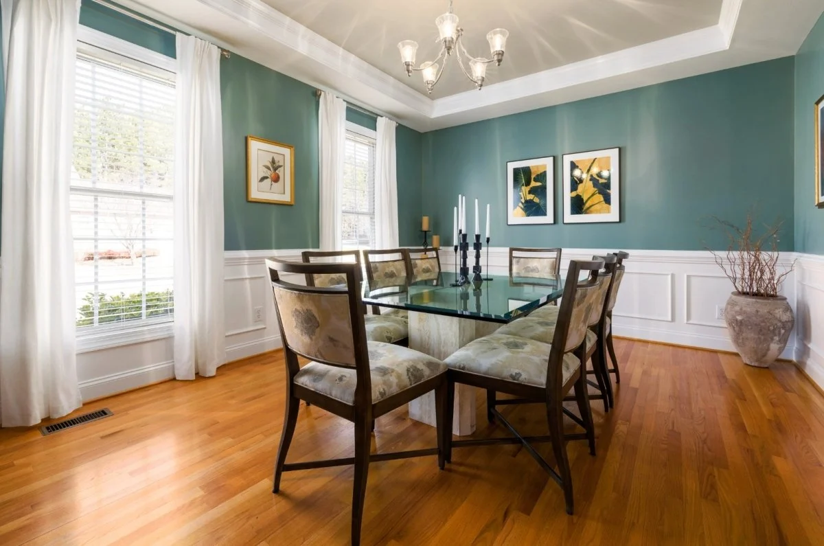 A real dining room with daylight streaming in, painted walls with a subtle eggshell sheen and a wooden table set simply