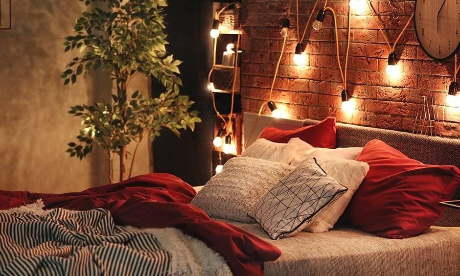 A small bedroom lit with warm bedside lamps and soft overhead light, with gentle shadows that add depth